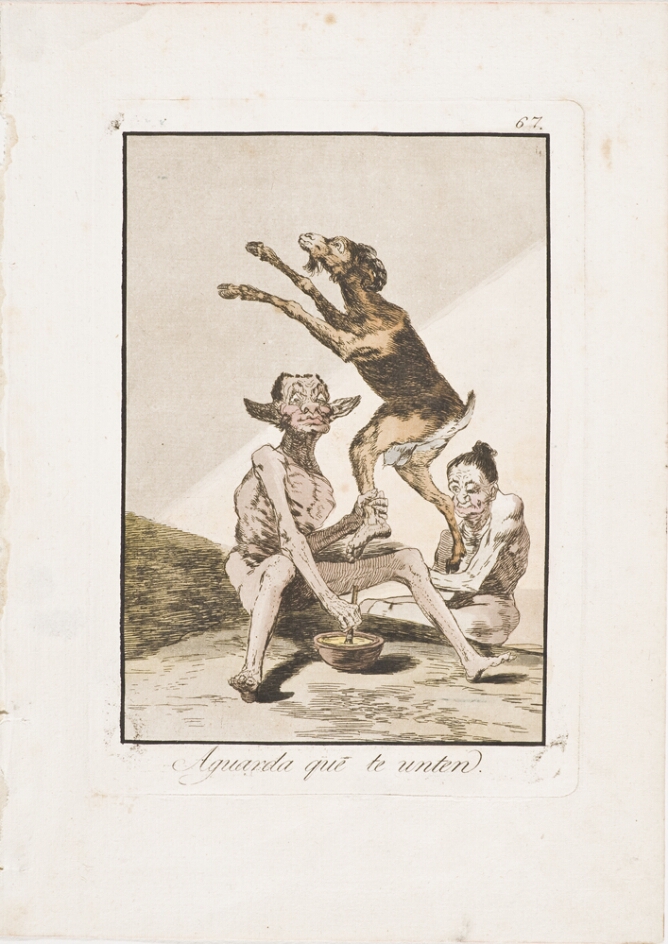 A color print of a seated grotesque figure holding a standing goat creature by its human ankle with one hand, while holding a brush-like instrument dipped in a bowl with the other. Another grotesque figures sits beside them