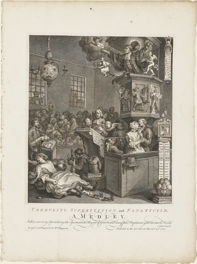 A black and white print of a man on a high pulpit holding strings attached to tiny figures of a witch and a demon figure above a crowd. In the foreground, a woman lies on the ground with rabbits emerging from her skirt