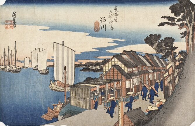 A color print of figures walking through a street lined with merchant shops alongside a seashore with boats at sail to the viewer's left