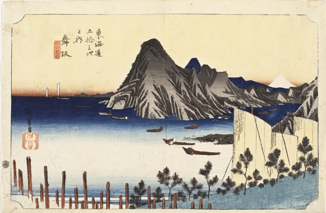 A color print of a view over a bay with boats, a headland and a white mountain in the background. In the foreground, large tops of sails seen above a tree-lined slope to the viewer's right
