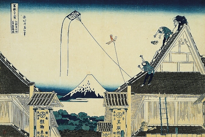 A color print showing a high vantage point of two shops flanking a snow-covered mountain in the distance. Figures sit and stand on the shop roof to the viewer's right, as two kites fly in the sky