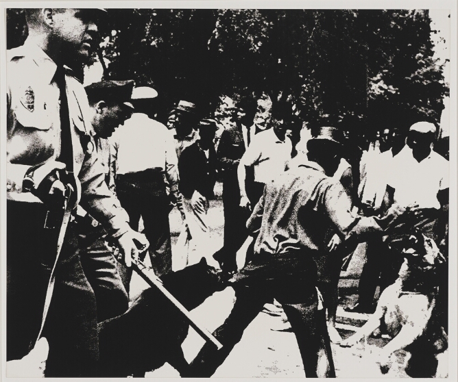 A black and white print of a standing Black man seen from the back, being attacked by police dogs, with white police officers to the viewer's left, one with a baton, and a group of Black men to the viewer's right
