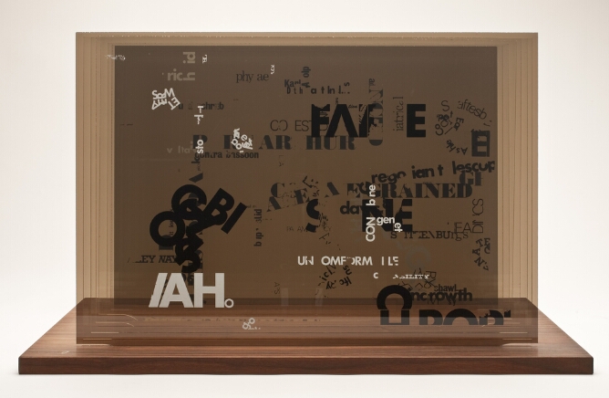 Fragments of black and white text printed on sheets of plexiglass set into a wooden base and assembled to form an abstract multi layered composition