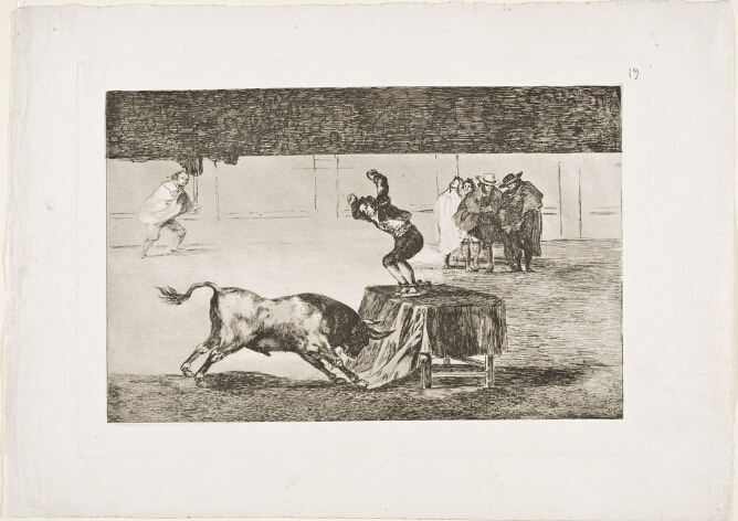 A black and white print of a man in an arena, standing on a table with arms raised and feet in a vice, facing a charging bull, with figures nearby