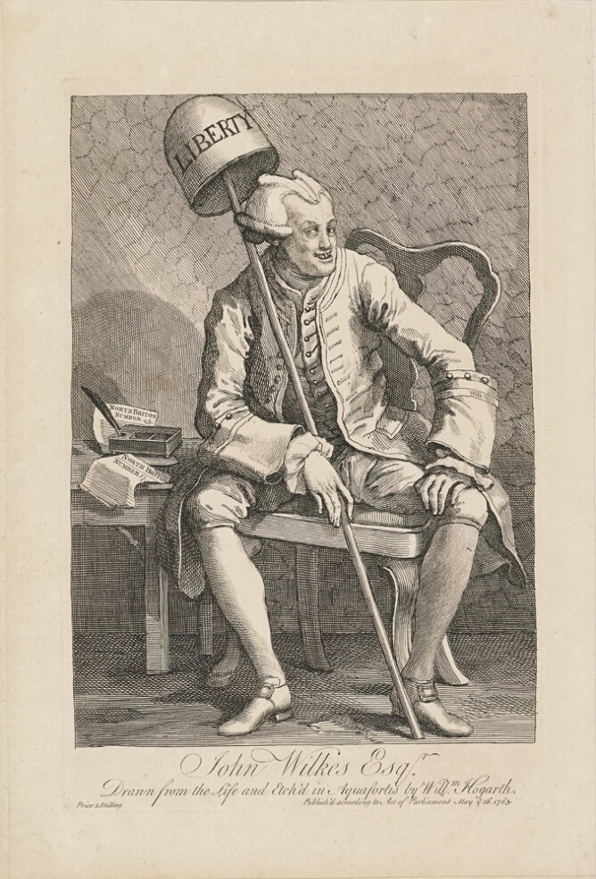 A black and white print of a man with a smirk sitting in a chair next to a desk, holding a staff with a cap on top with an inscription that reads LIBERTY